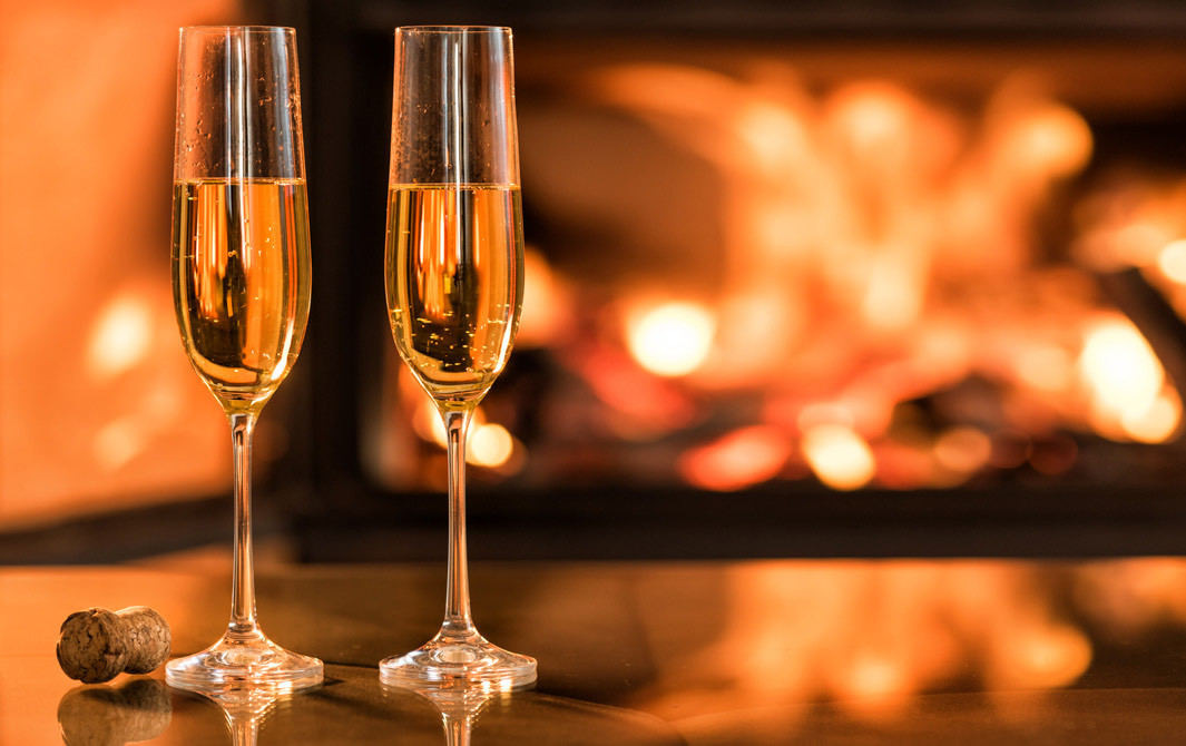 two glasses of champagne in front of a fire