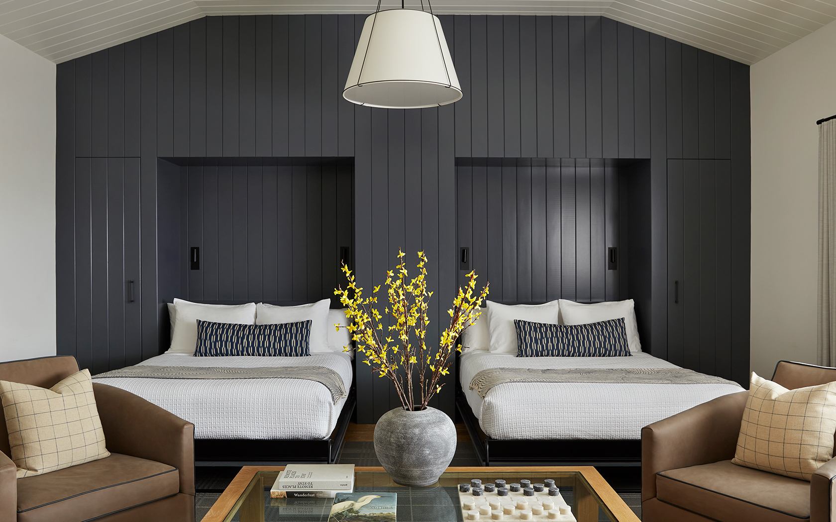 a room with two beds and a vase of yellow flowers