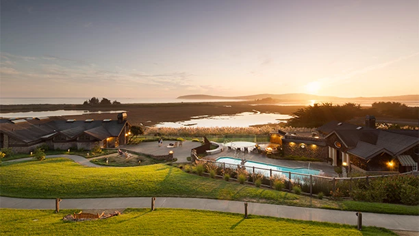 a pool and a house with a body of water in the background