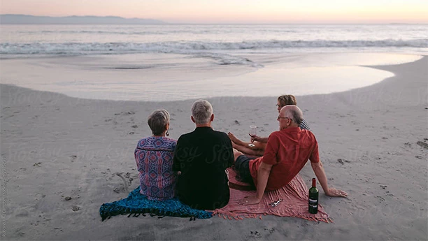 a group of people sitting on a blanket on a beach