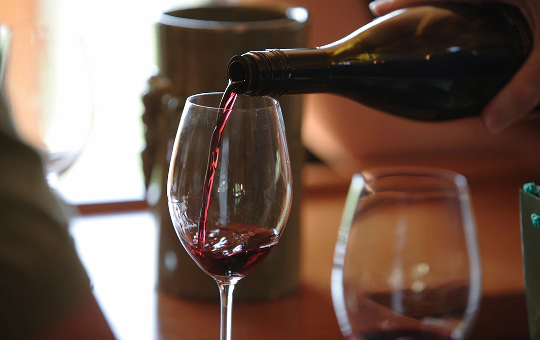 a person pouring red wine into a glass