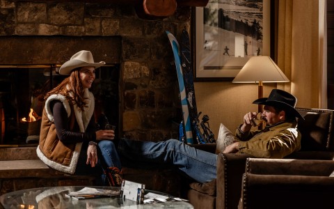 a woman in cowboy hats sitting on a couch with a man in a hat
