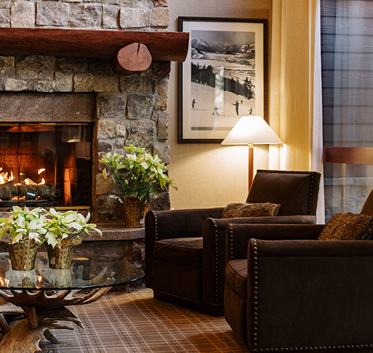 a fireplace in a room with chairs and a lamp