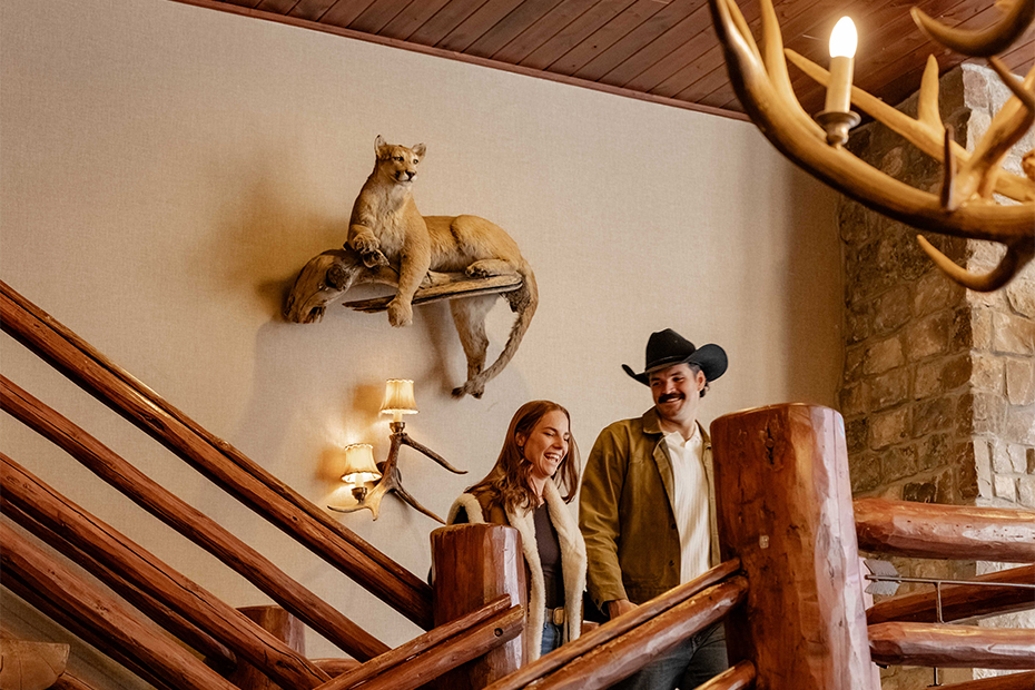a man and woman standing on a staircase with a lion on the wall