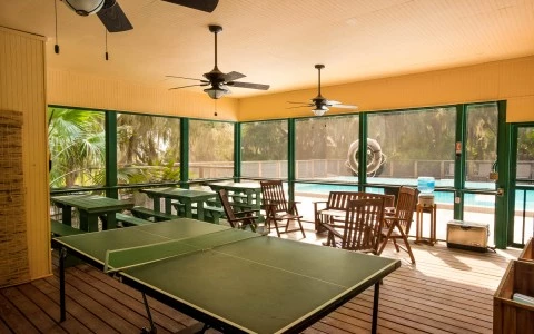 view of pool from inside porch with ping pong table 