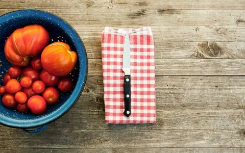 bowl of tomatoes with a knife beside it 