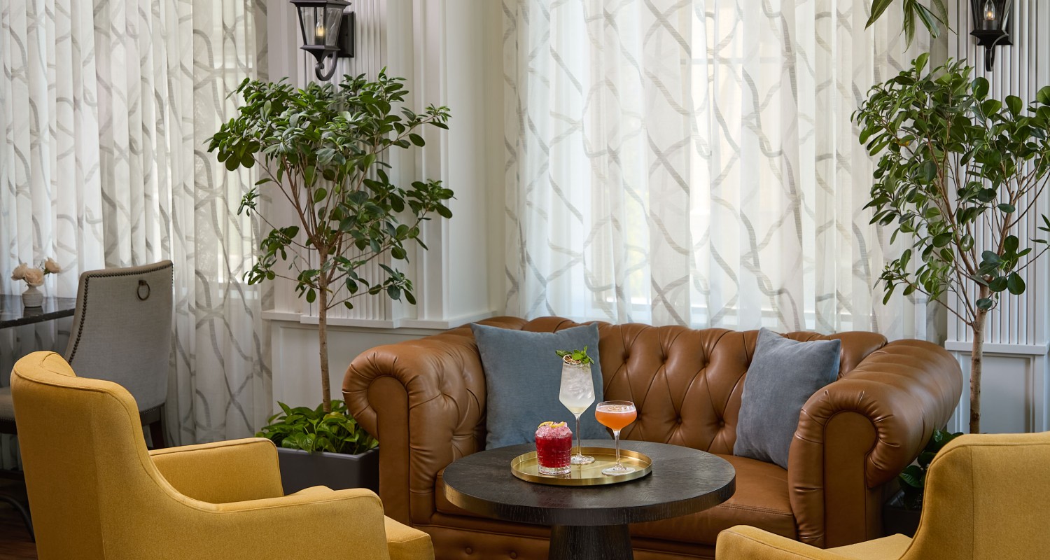 a couch with drinks on a table in a room with curtains