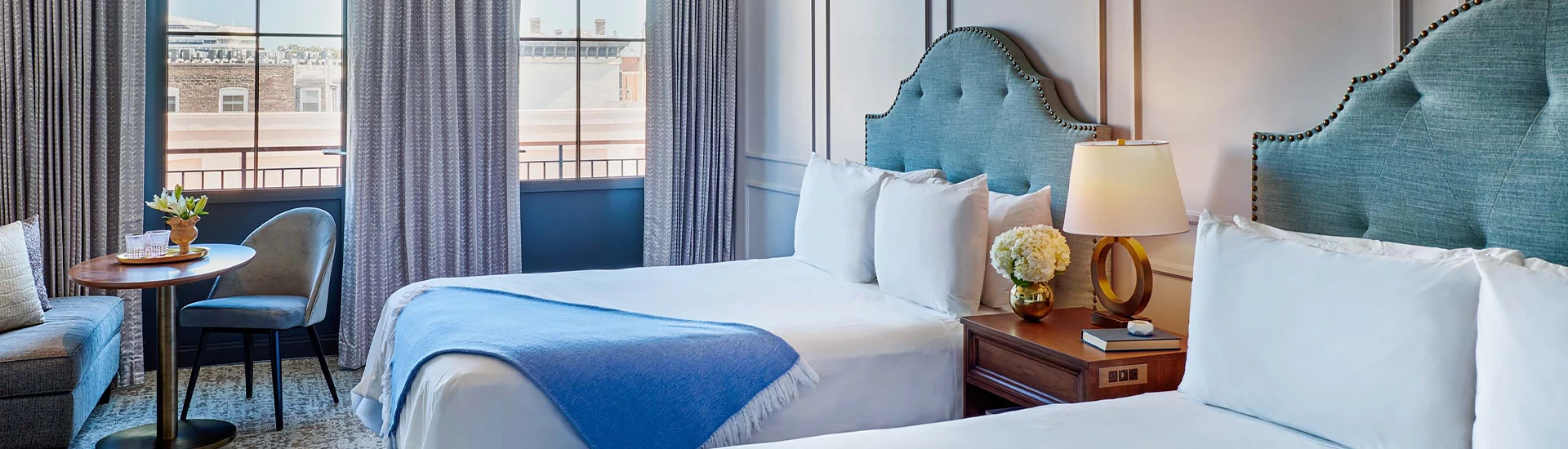 A hotel room with two beds, a window, and a small table