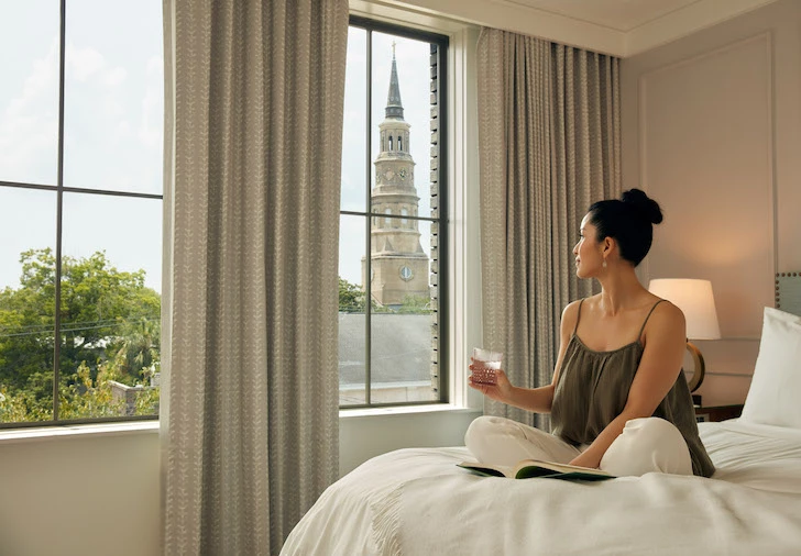 a woman sitting on a bed looking out a window