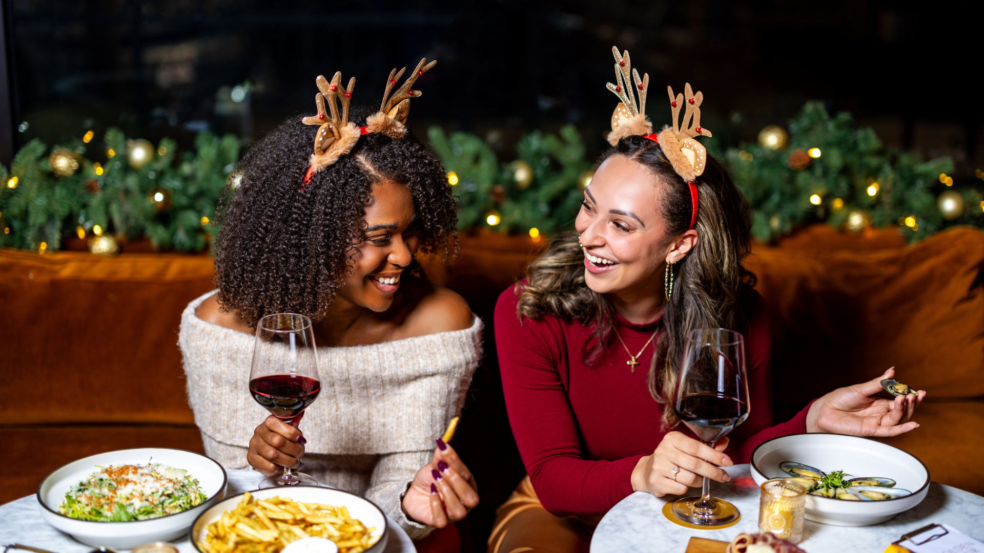 a group of women sitting at a table with food and drinks