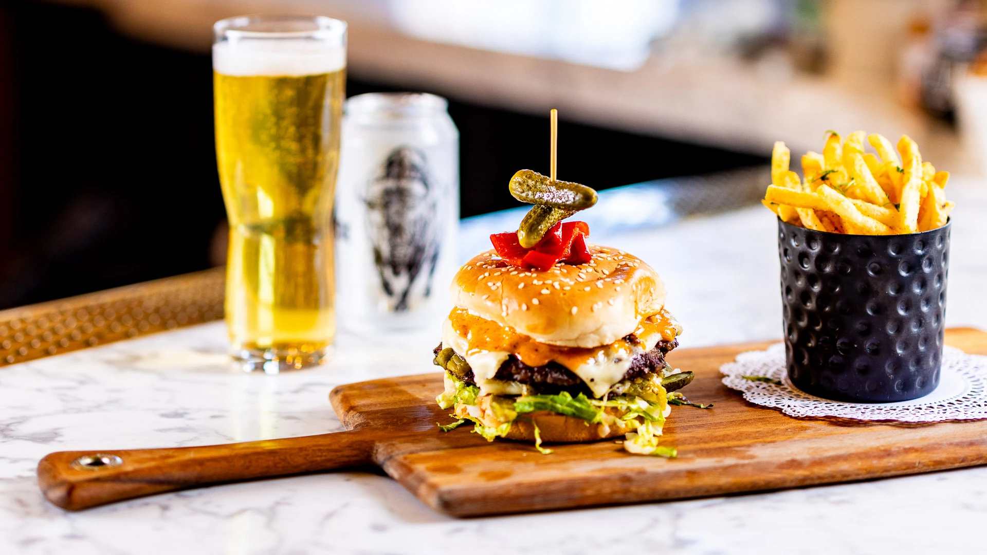 A burger with fries and a beer on a table