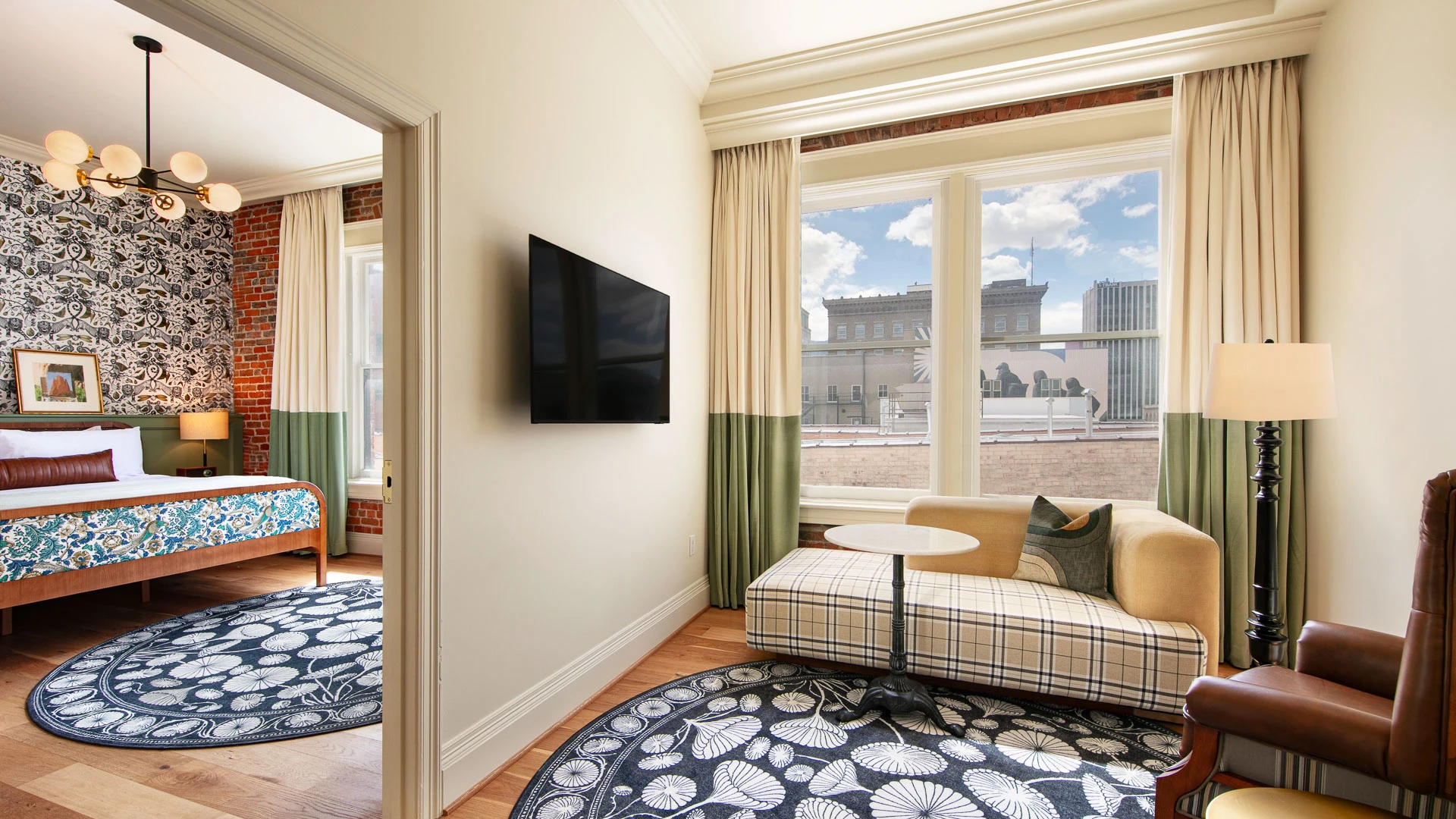 A wide view of a hotel room with a sitting area and bedroom in the background.