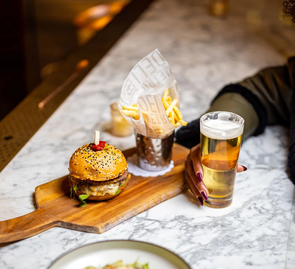 A burger and fries with a beer on a marble countertop