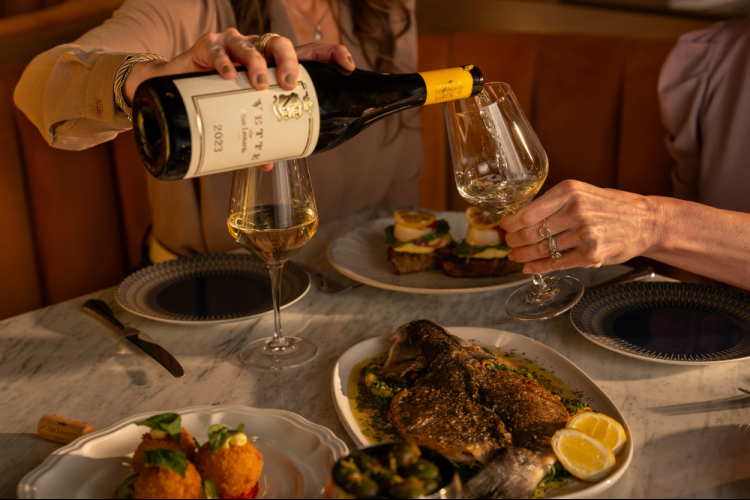 a person pouring wine into a glass