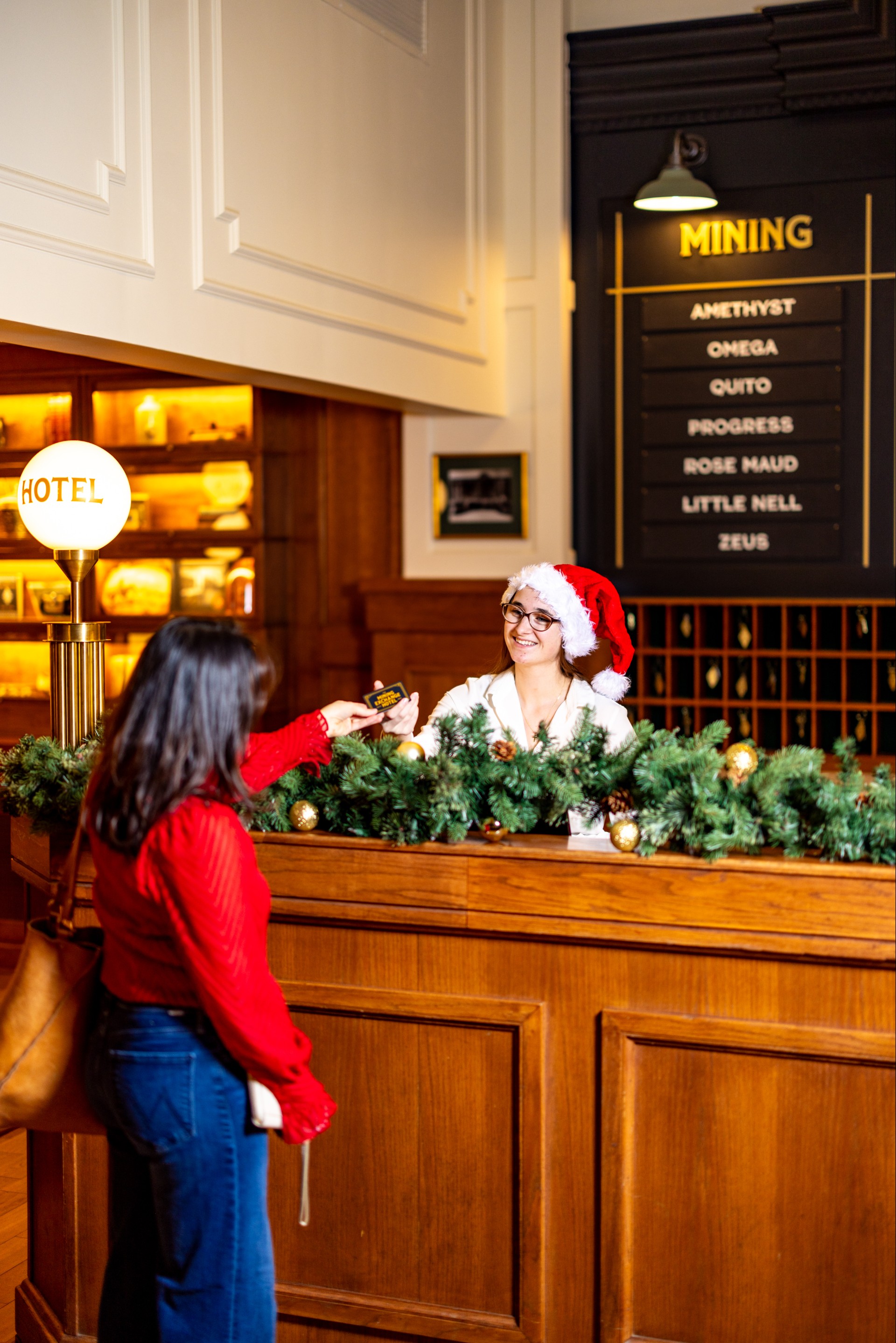 a woman standing behind a counter with a woman in a santa hat