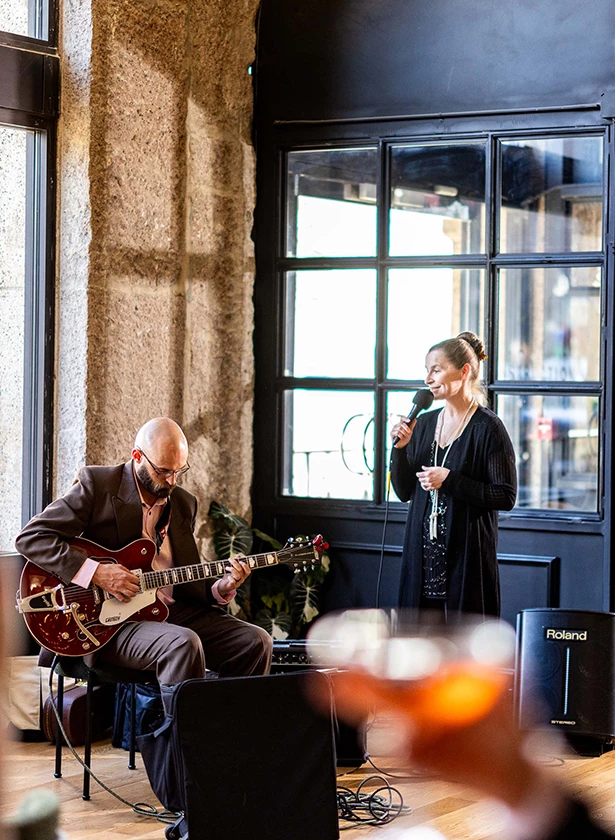 A man playing guitar and a woman singing in a lounge.