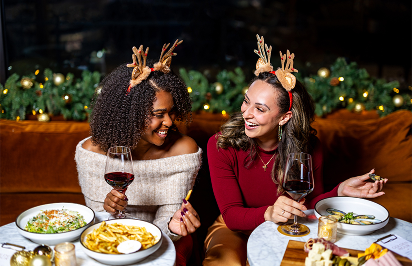 a group of women sitting at a table with food and drinks