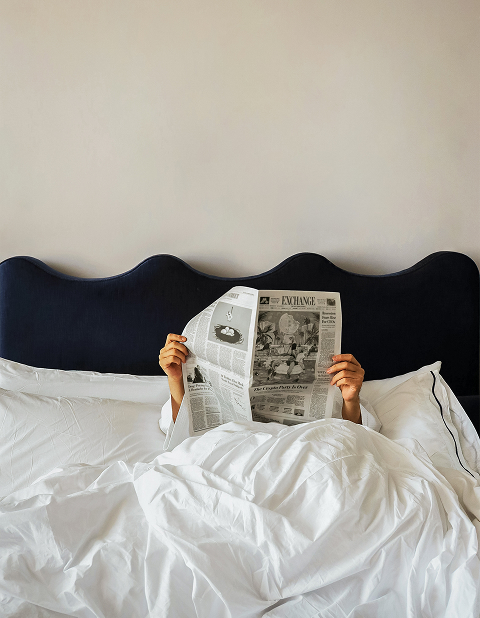 a person reading a newspaper in bed