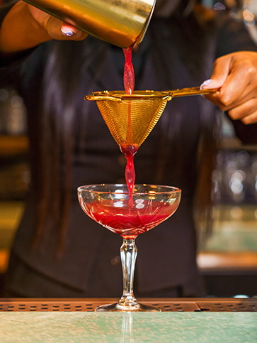 a person pouring a drink into a glass