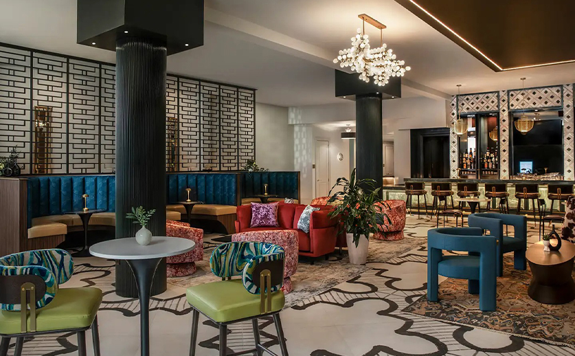 a room with a large chandelier and tables and chairs
