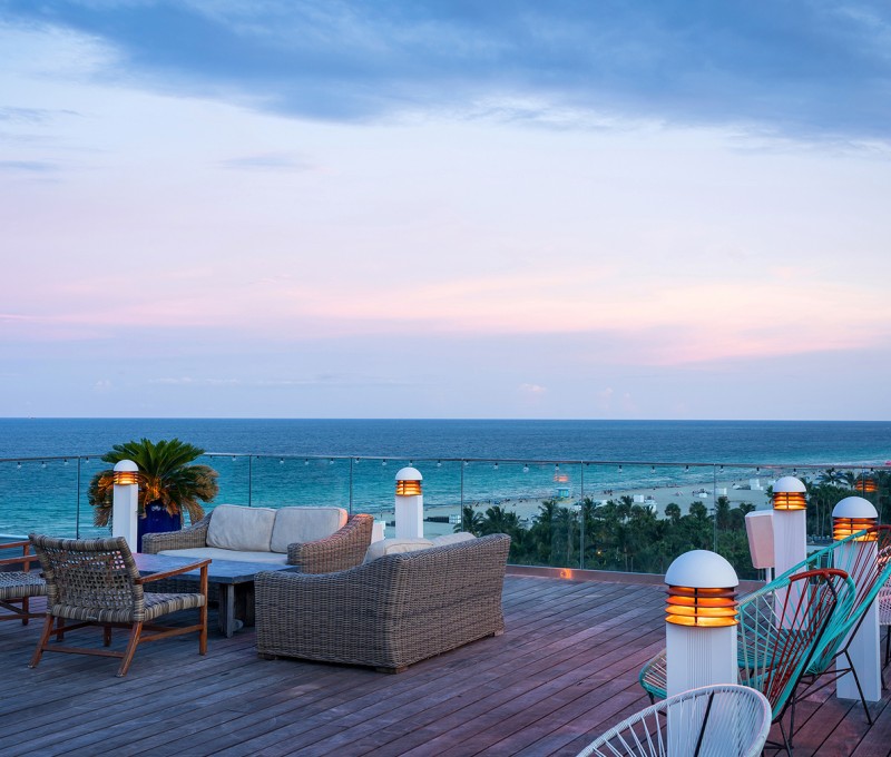 a deck with chairs and tables overlooking a body of water
