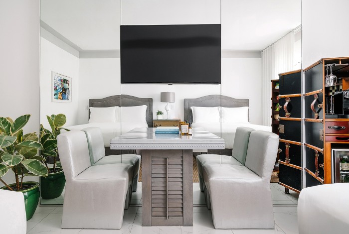 a bedroom with two beds, table and chairs