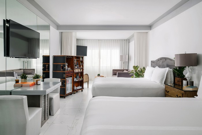 a room with a two beds, table and chairs