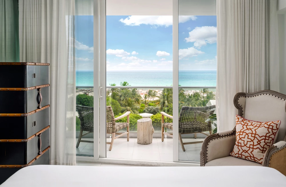a room with a table chairs and a window with a view of the ocean