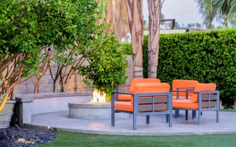 A small outdoor seating area with a fire pit and orange chairs