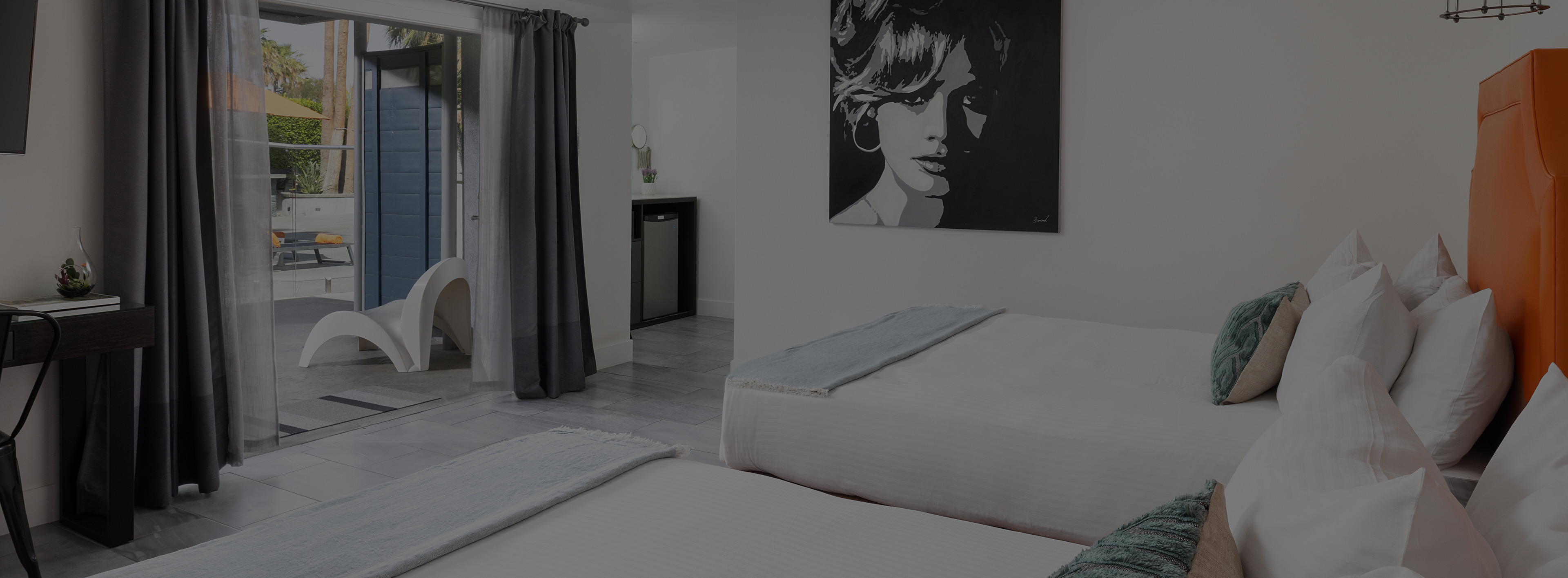 A hotel room with two beds, a glass door leading to an outdoor area, and a desk.