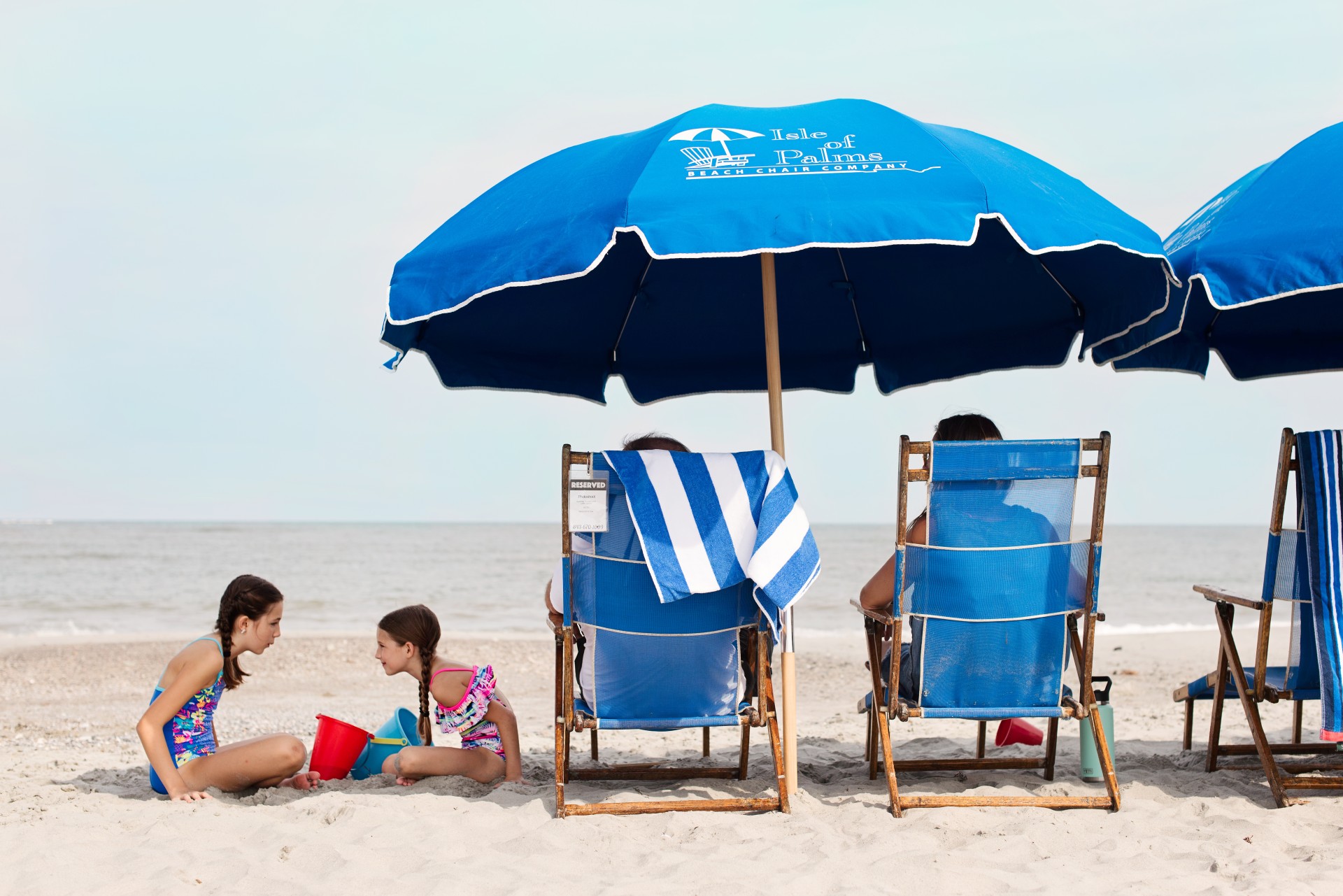 a group of people sitting under a blue umbrella on a beach