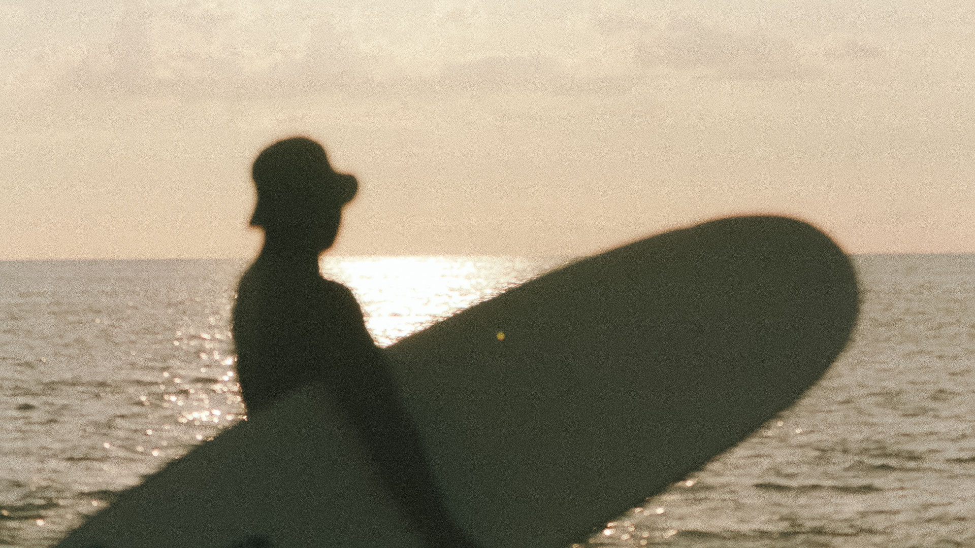 a silhouette of a man holding a surfboard in the water