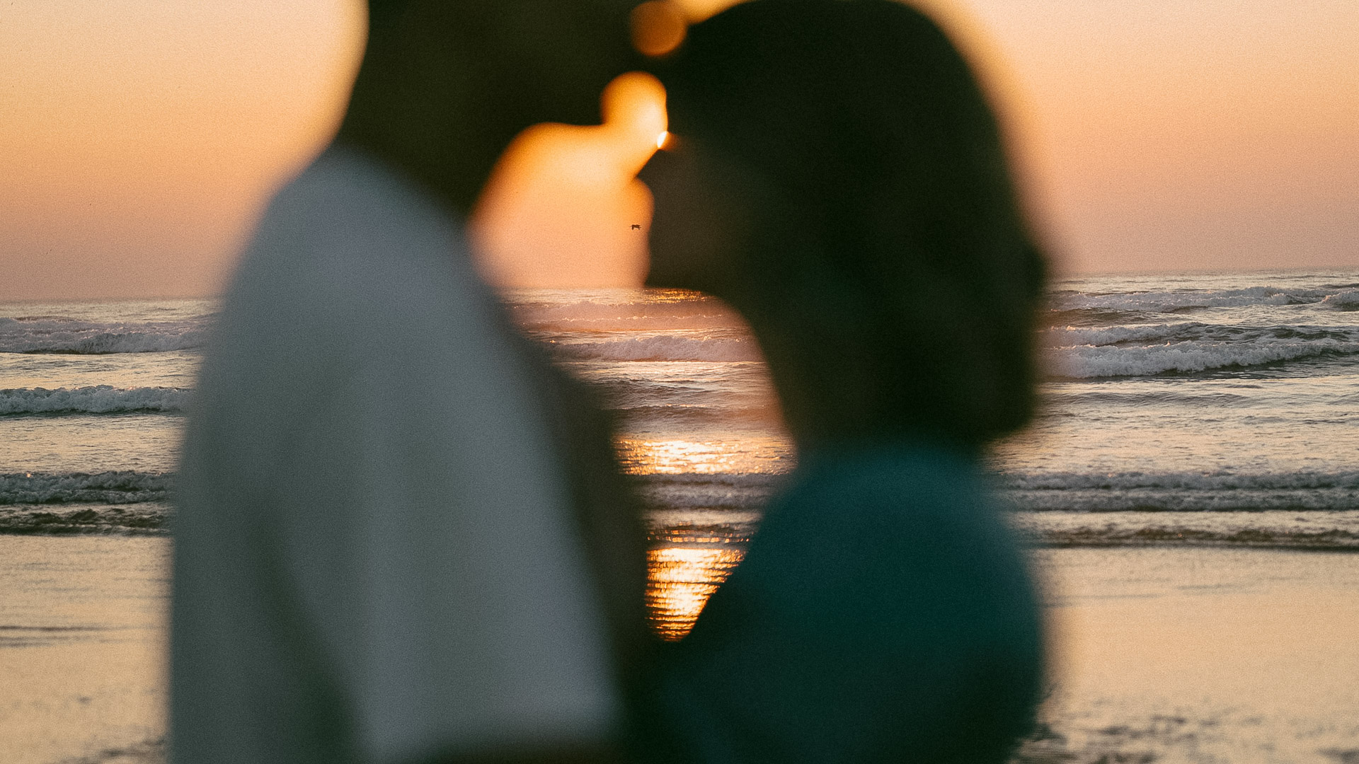 a man and woman kissing at the beach