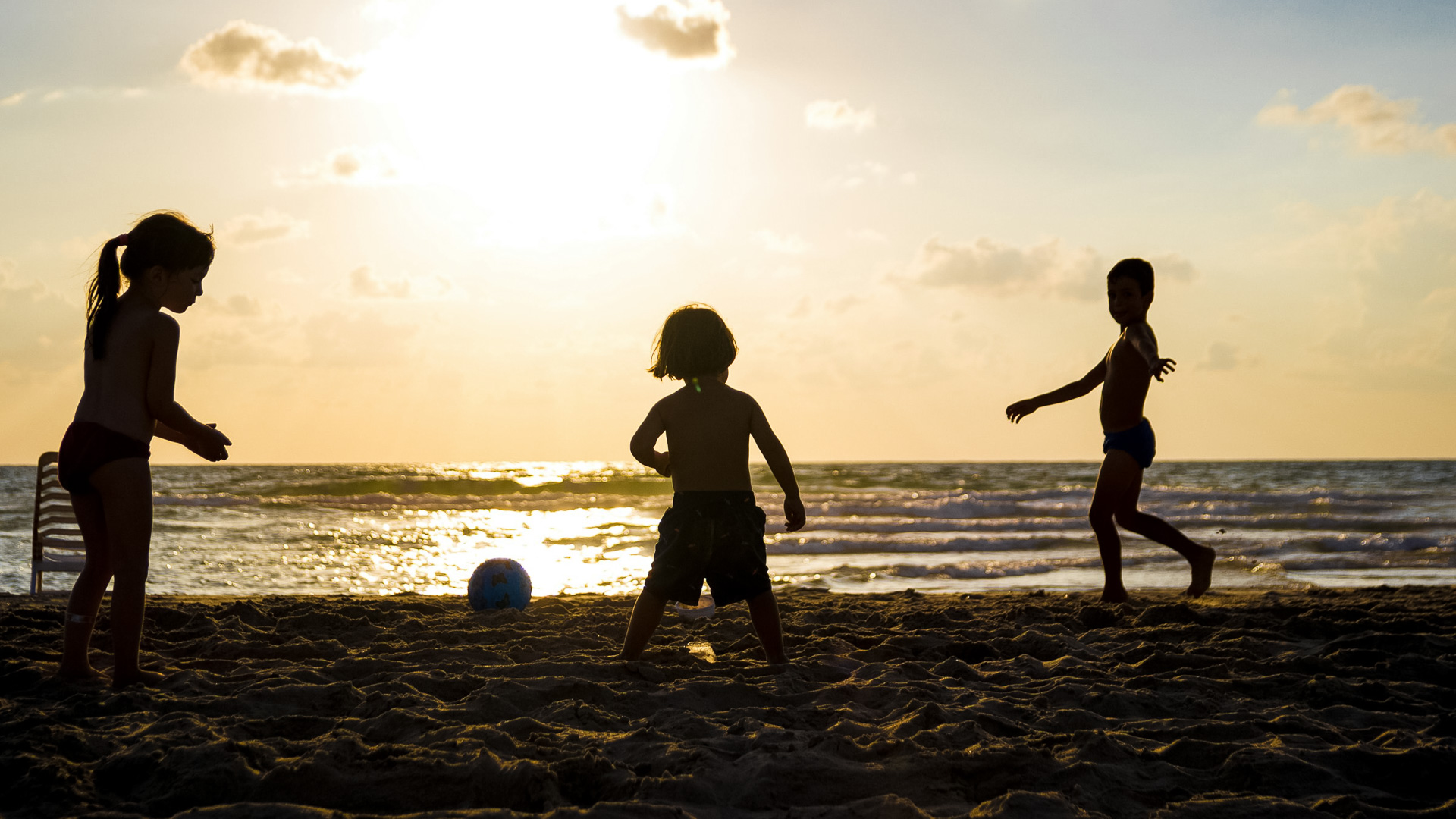 a group of kids playing with a ball on a beach