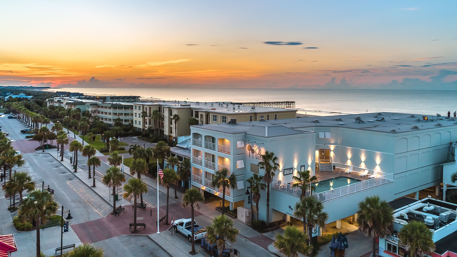 a beachfront resort with palm trees and a sunset