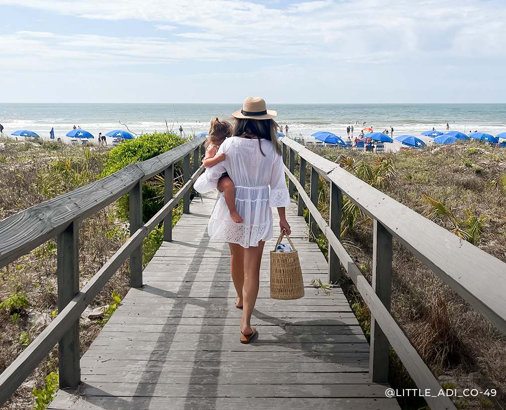 a woman carrying a child walking on a boardwalk