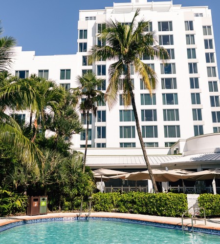 a pool with palm trees in front of a building