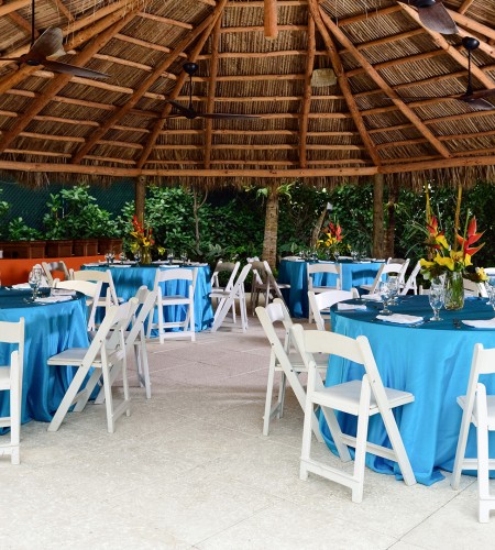 a round tables and chairs under a straw roof