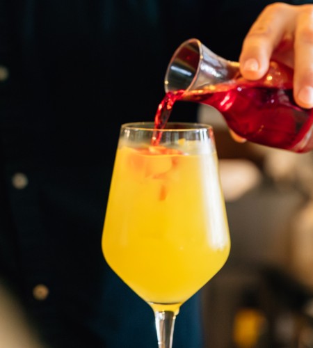 a person pouring a drink into a glass