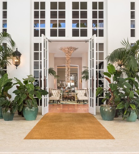 a white building with a door open and plants in pots
