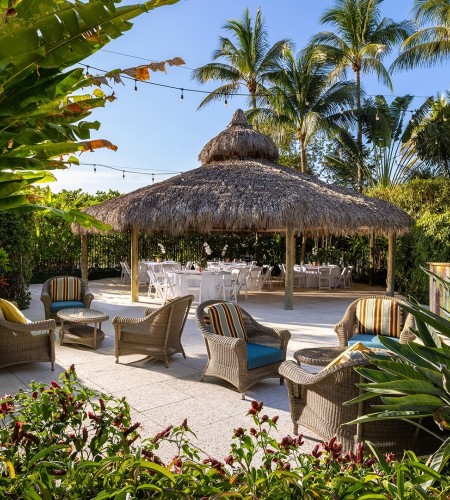 a patio with chairs and a straw umbrella