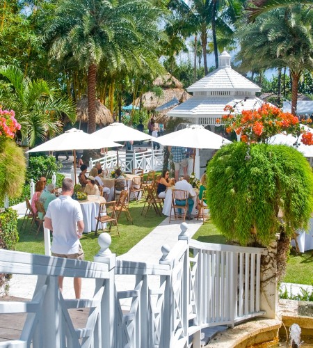 a group of people outside with tables and chairs