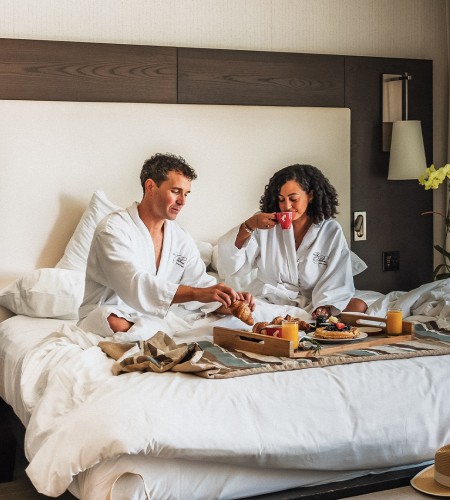 a man and woman in white robes sitting in a bed with food