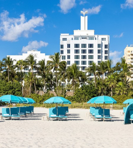 a beach with blue umbrellas and lounge chairs