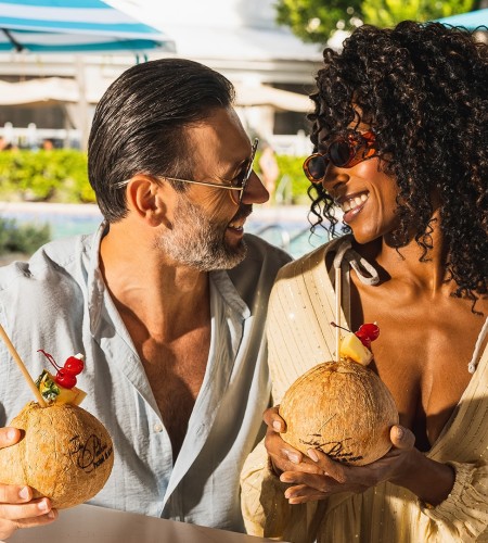 a man and woman holding coconuts