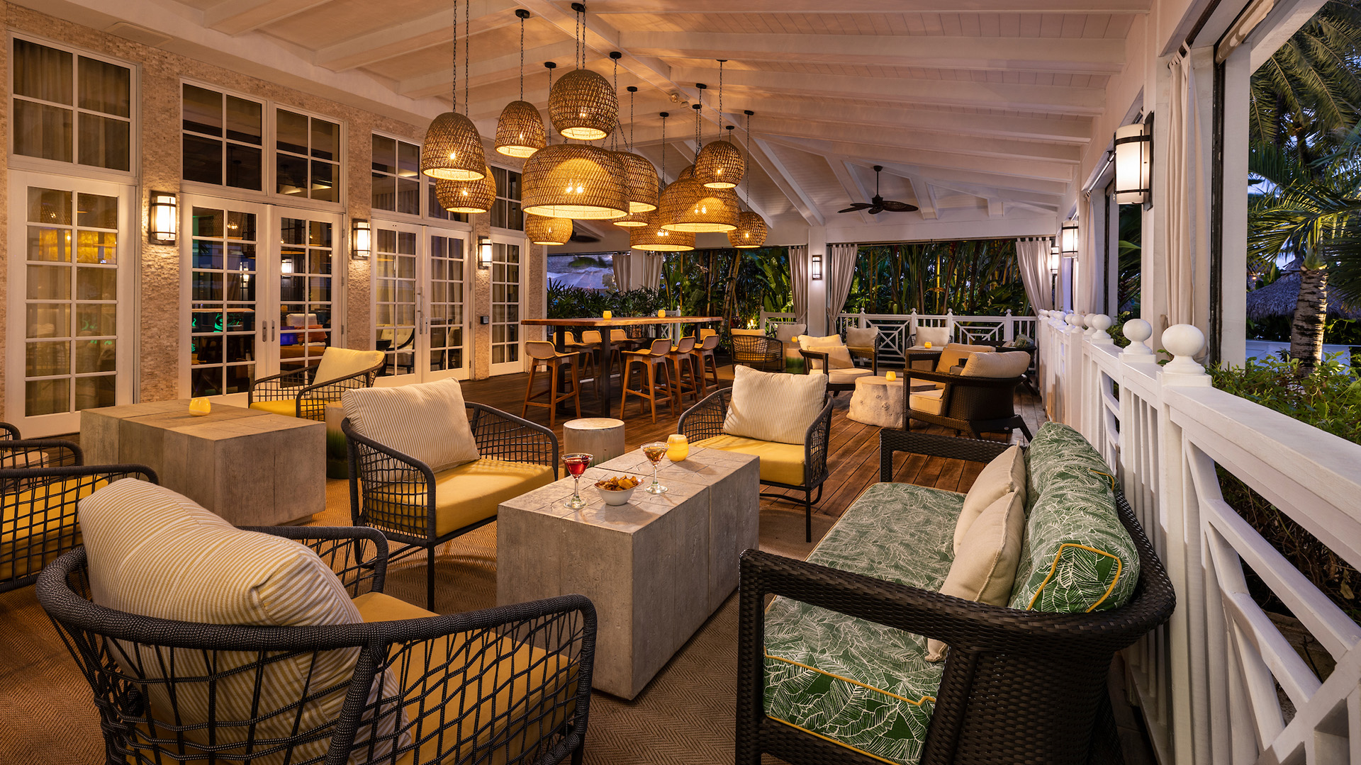 A stylish outdoor bar with wicker furniture and candlelight.