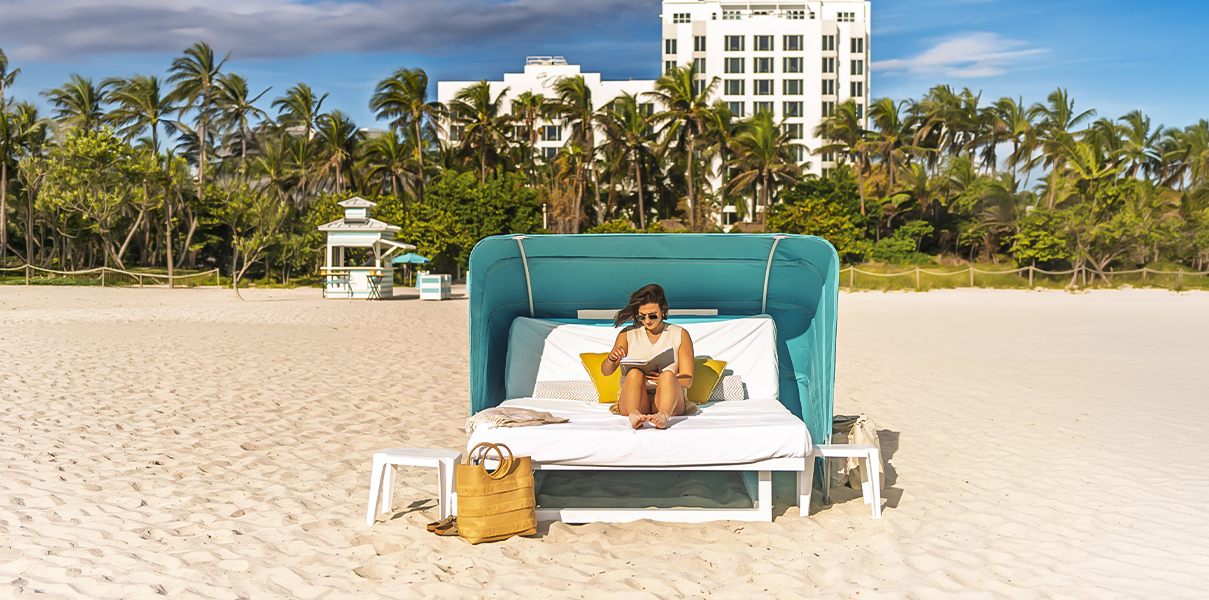 a woman sitting on a bed on a beach