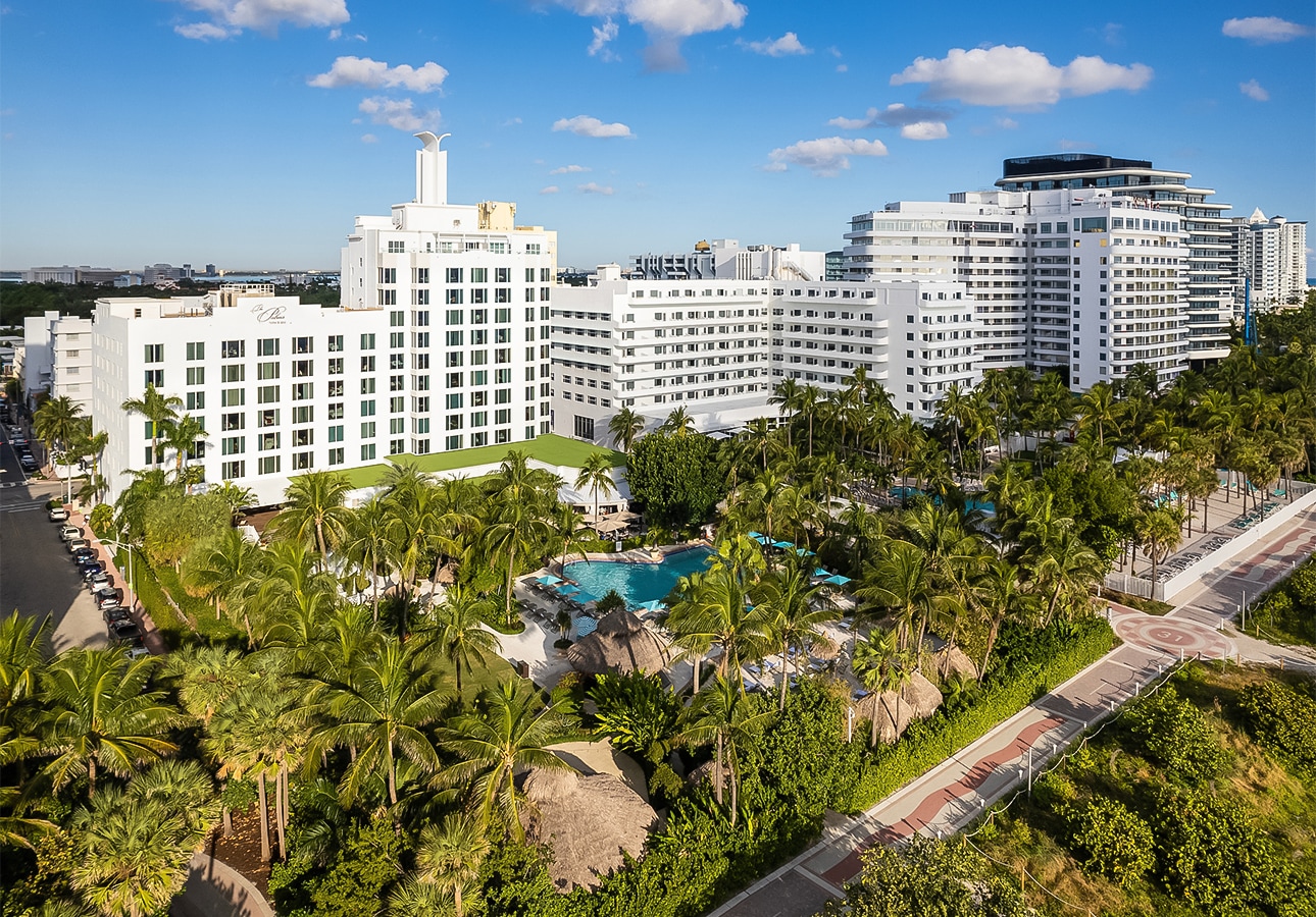 a large white building with palm trees and a pool