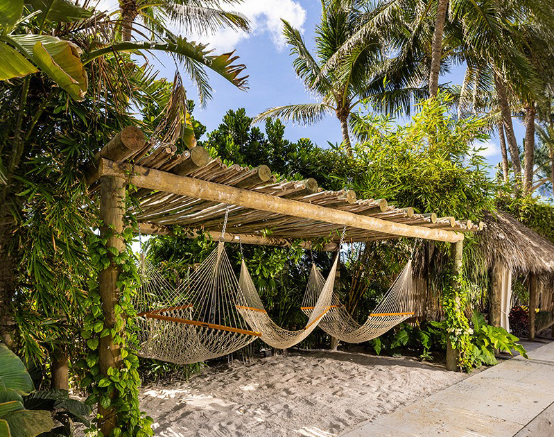 hammocks under a wooden structure with palm trees and blue sky