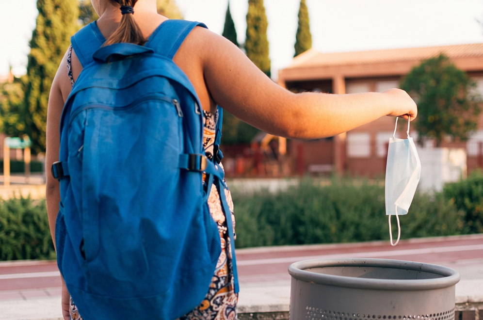 a woman wearing a backpack and holding a face mask